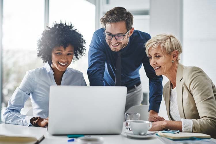 Drei Kolleg*innen arbeiten an einem Laptop