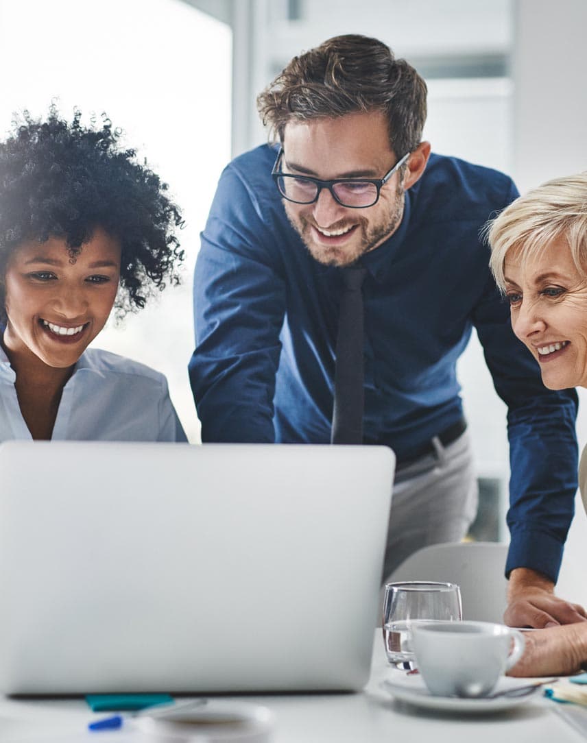 Drei Kolleg*innen arbeiten an einem Laptop