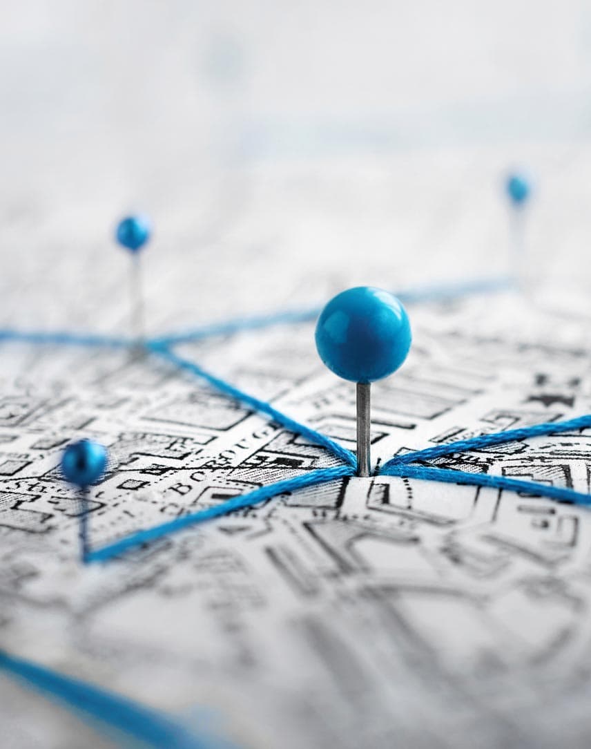 Ein Stadtplan mit stilisierten blauen Stecknadeln, die per blauen Fäden verbunden sind und eine Vernetzung symbolisieren