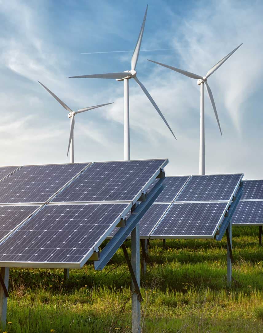 Photovoltaik-Module auf einer Freifläche, im Hintergrund Windräder