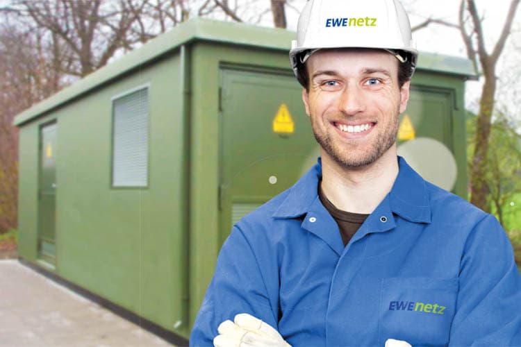 Ein Techniker von EWE NETZ mit Blaumann und Schutzhelm vor einem Umspannkasten