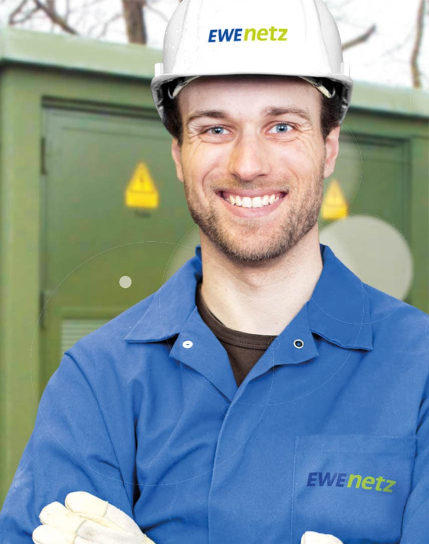 Ein Techniker von EWE NETZ mit Blaumann und Schutzhelm vor einem Umspannkasten