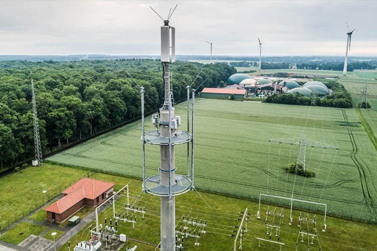 Ein Mobilfunk-Sendemast, im Hintergrund eine Biogasanlage