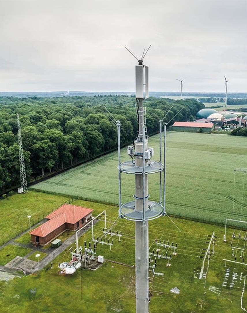 Ein Mobilfunk-Sendemast, im Hintergrund eine Biogasanlage