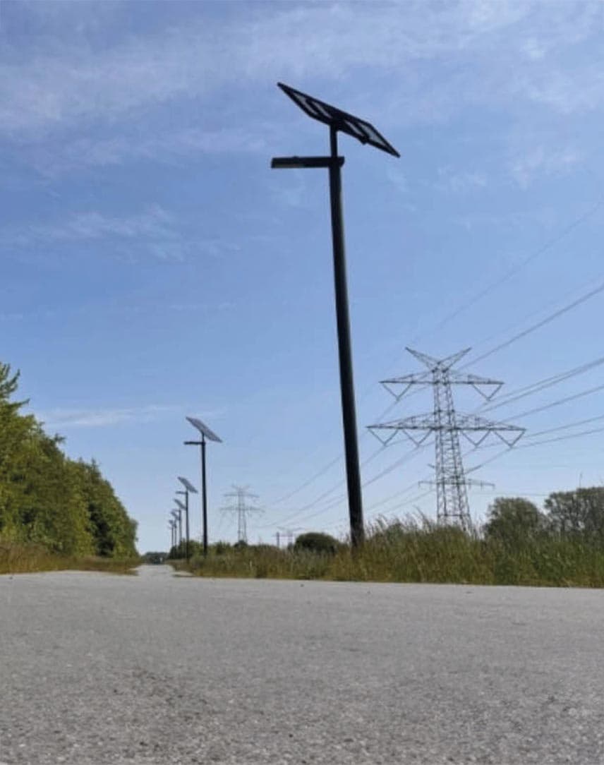 Solarleuchten an einem Straßenrand, dahinter Strommasten