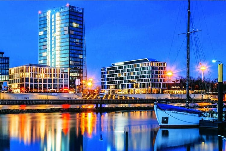 Skyline an der Weser mit Segelboot im Vordergrund zur blauen Stunde