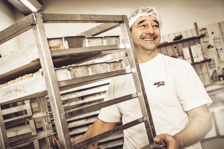 Ein Bäcker mit einem Regal in einer Bäckerei