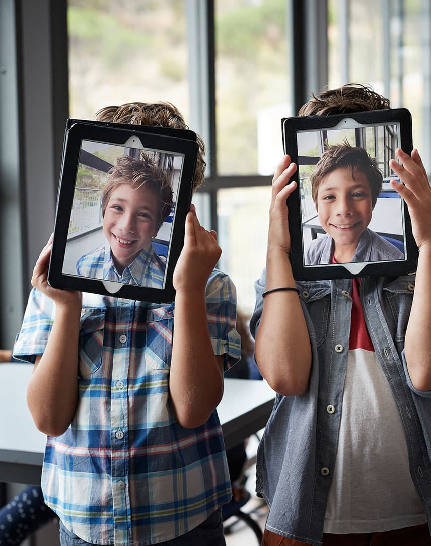 Kindergesichter auf Tablets, die die Kinder hochhalten