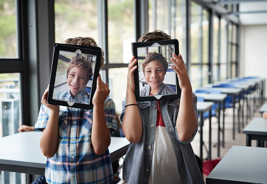 Kindergesichter auf Tablets, die die Kinder hochhalten