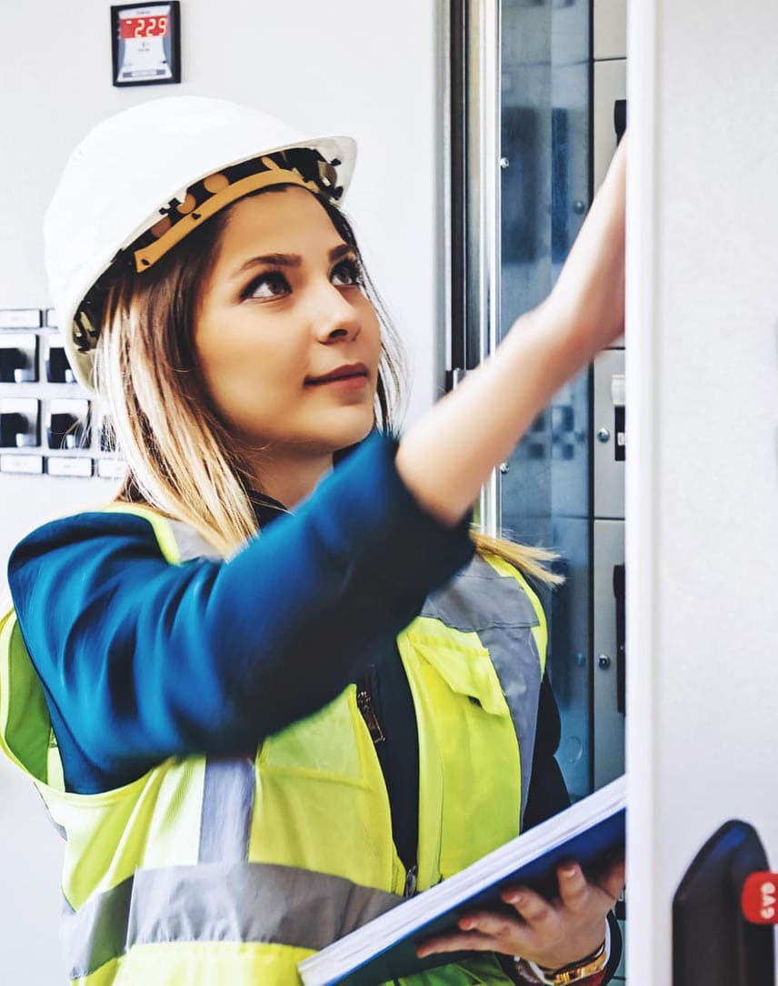 Eine Mitarbeiterin mit Helm und Schutzweste in einem Kraftwerk