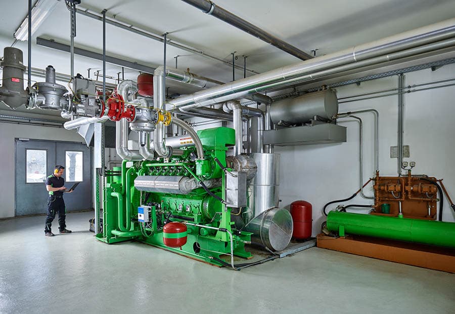 Ein grünes Blockheizkraftwerk, das von einem Servicetechniker geprüft wird