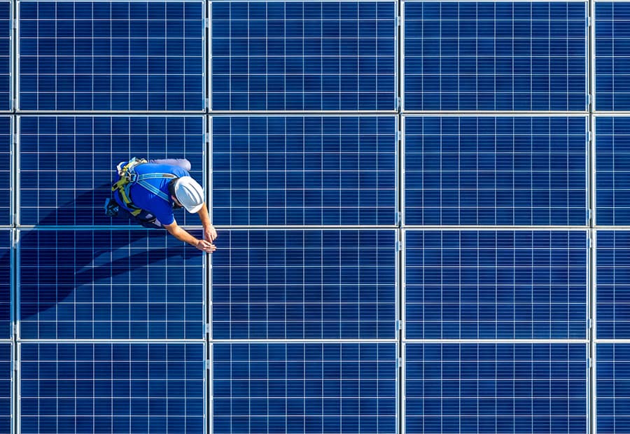 Ein Techniker mit Helm, der auf einer PV-Fläche kniet