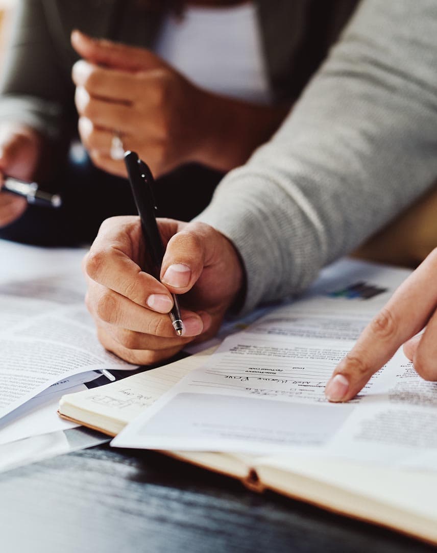 Die Hände von Personen, die in Unterlagen etwas eintragen