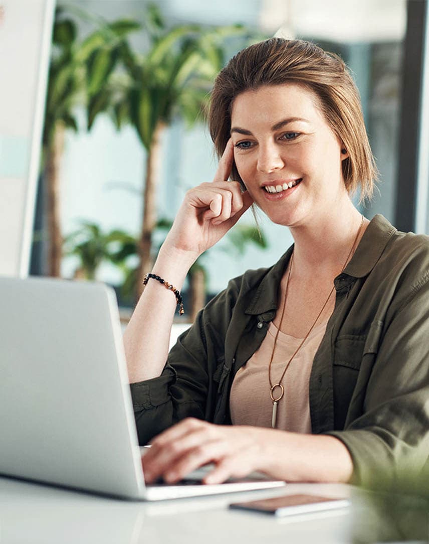 Eine Frau guckt auf ein Notebook und hört interessiert zu.