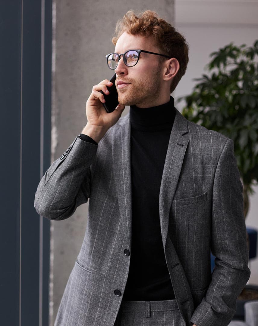 Ein Mann im Anzug steht in einem Büro und telefoniert.