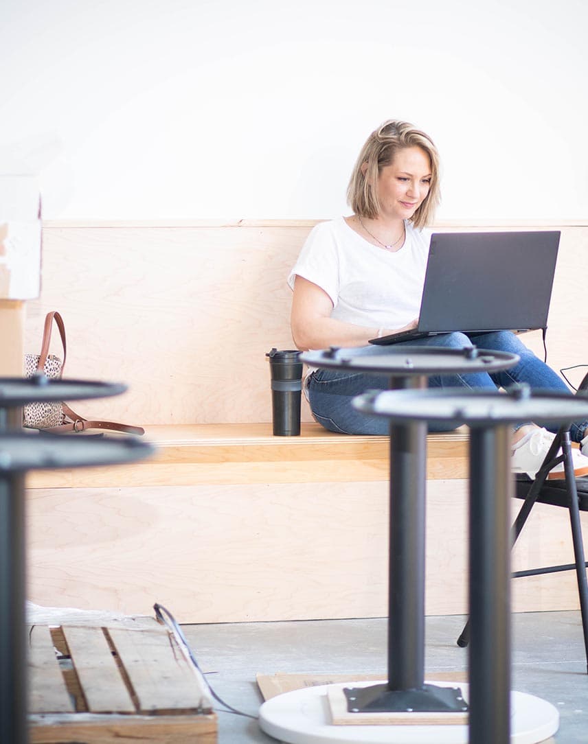 Eine Unternehmerin, die mit Laptop in einem Geschäftsraum sitzt, der gerade umgebaut wird