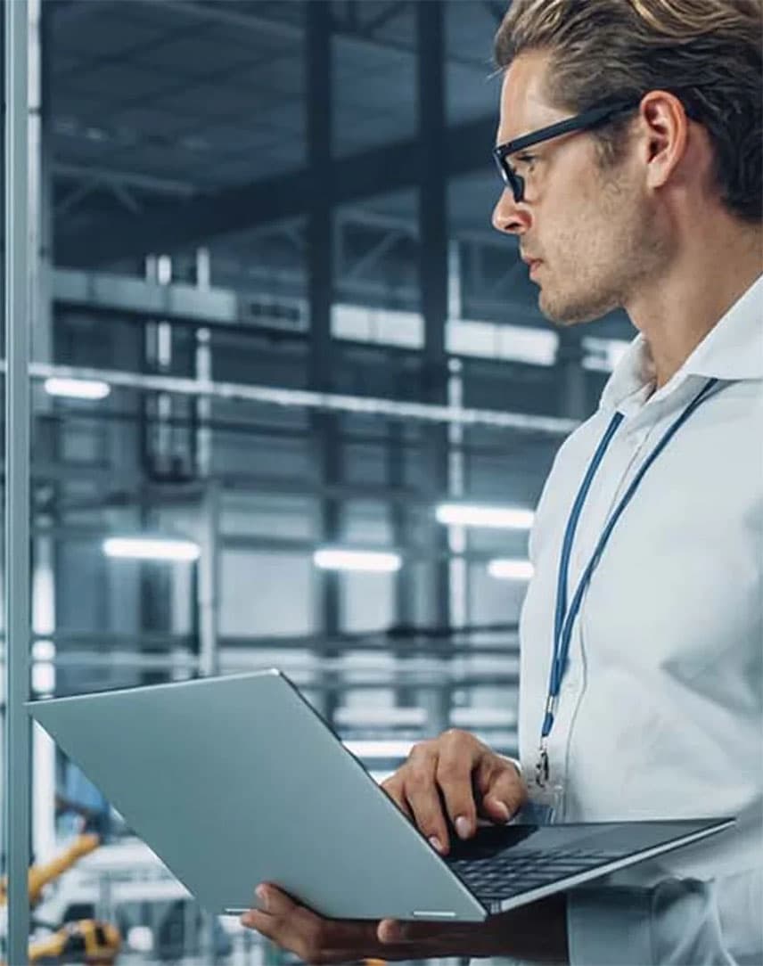Ein Ingenieur mit Laptop in einer Produktionshalle