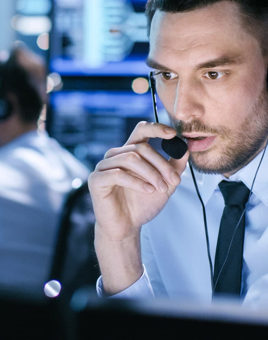 Ein Mann spricht in einem blau erleuchteten Kontrollraum in ein Headset