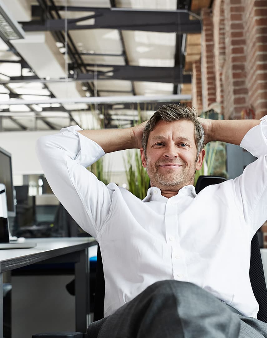 Mann sitzt entspannt in einem Bürostuhl im Büro