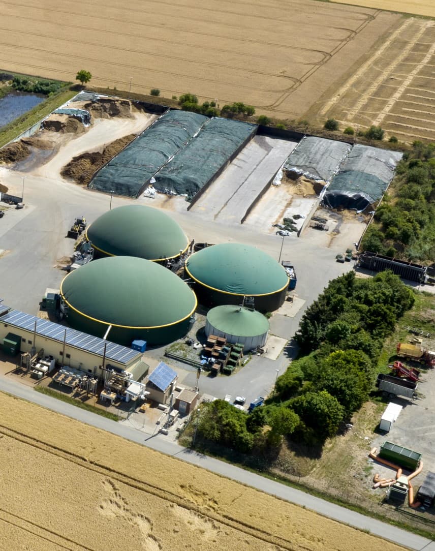 Eine Luftbildaufnahme einer Biogasanlage, die von landwirtschaftlicher Fläche umgeben ist