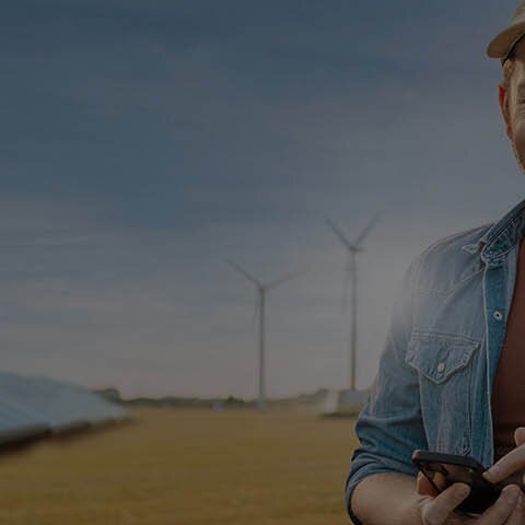 Ein Landwirt in einem Feld vor Solaranlage, Windrädern und Biogasanlage