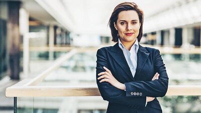 Eine Frau in einem Unternehmensgebäude, die die Arme verschränkt