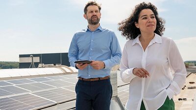 Eine Frau und ein Mann auf einem Firmendach mit PV-Anlage