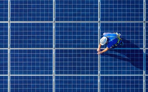 Die Bedeutung der Solarpflicht in Niedersachsen Ein PV-Techniker auf PV-Modulen von oben