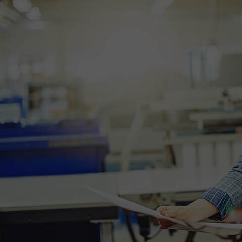 Eine junge Frau, die einen Proof in einer Druckerei überprüft.