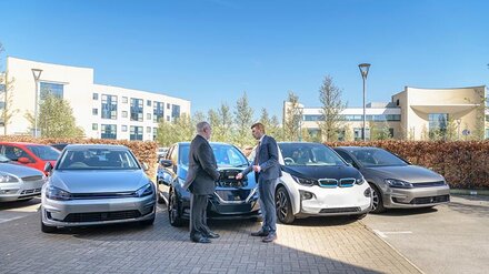 Zwei Männer in Anzügen vor parkenden E-Autos