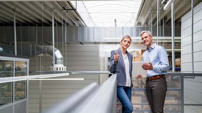 Eine Frau und ein Mann mit Tablet in einer Werkshalle