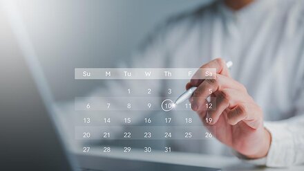 Eine Person im weißen Hemd vor einem Holo-Kalender über einem Laptop
