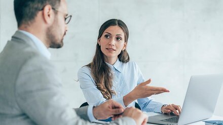 Frau erklärt Mann etwas an Rechner
