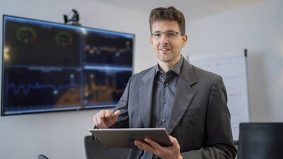 Mann mit Brille und Jacket und Tablet in der Hand
