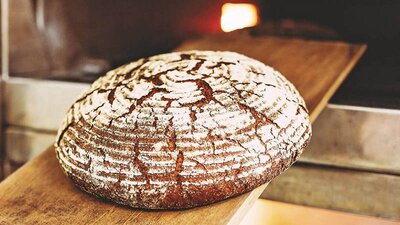 Ein Brot, das auf einem Brett aus dem Ofen geholt wird