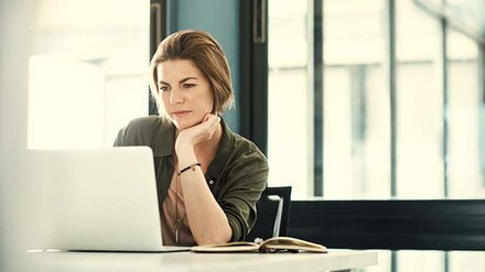 Eine Frau, die interessiert etwas auf einem Notebook-Bildschirm ansieht