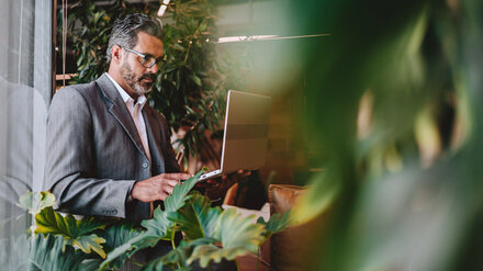 Ein Mann mit Laptop zwischen Pflanzen