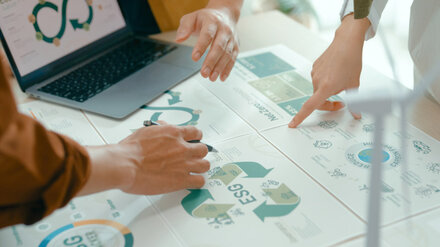 Drei Personen besprechen einen Plan am Schreibtisch.