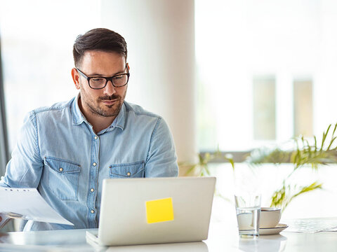 Ein Mann im Jeanshemd, der auf seinen Rechner guckt Webinar-Inhalte