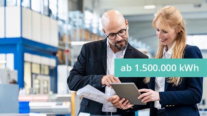 Eine Frau und ein Mann prüfen etwas auf einem Tablet in einer Produktionshalle