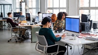 Mehrere Personen an Computern in Großraumbüro