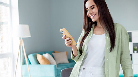 Braunhaarige Frau mit Smartphone in der Hand