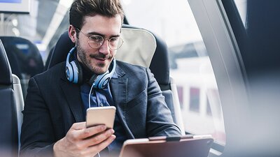 Ein Mann mit Kopfhörer und Endgeräten in einem Zug