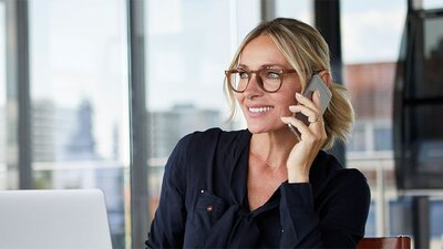 Blonde Frau mit Brille am Smartphone