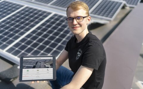 EWE business Referenz Müller & Egerer PV Junger Mann mit Brille und Tablet vor PV-Anlage