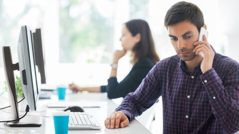 Ein Mann im Büro telefoniert am Smartphone