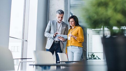Gute Gründe für Glasfaser von EWE Mann und Frau im casual Business-Look am Tablet in Büro