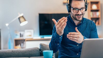 Mann mit Headset erklärt etwas vor dem Laptop