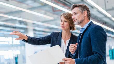 Geschaeftsleute bei einer Besprechung in einer Produktionshalle 800x450.jpg