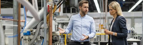 EWE business Regelenergie Eine Frau und ein Mann in einer Produktionshalle